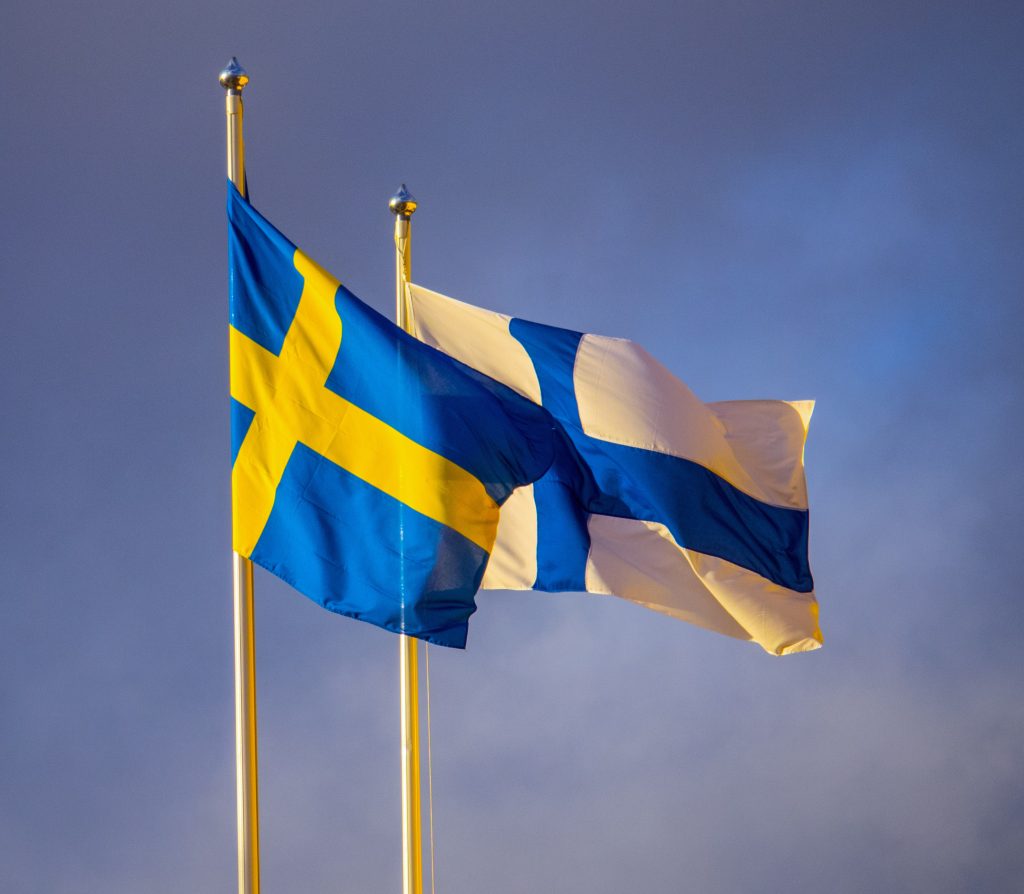 En svensk och en finsk flagga bredvid varandra utomhus.