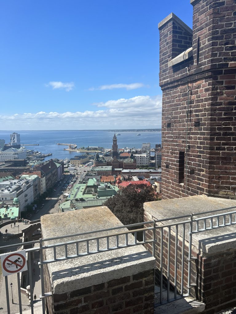 Ärgade tak, stenbyggnader och kyrktorn mot bakgrund av Helsingborgs hav. 